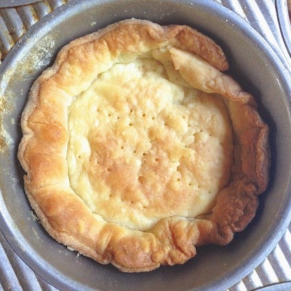 Prebaked pastry crust slumped into the bottom of a tart pan.