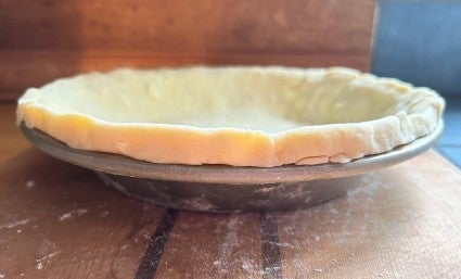 Pie crust laid in a 9" round pie pan, with a 1/2"-tall pastry rim around the edge.