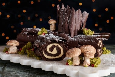 Chocolate Buche de Noel with Cookie Butter Whipped Ganache seen from the side with edible woodland decorations.