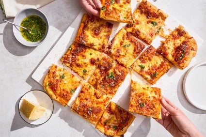 A sliced up Flaky Puff Crust Pizza with pieces being taken out