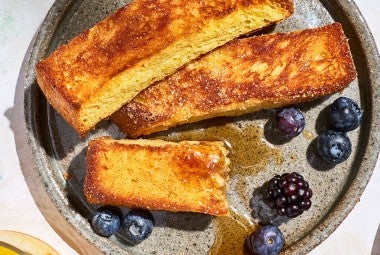 French Toast Sticks on a plate with fresh berries and maple drizzle.