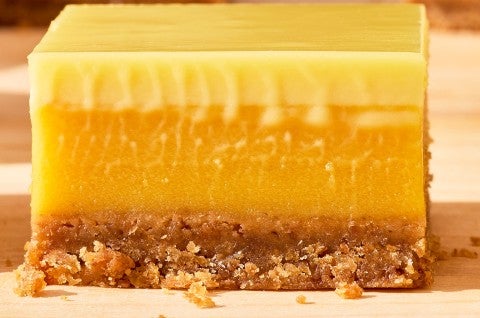A Passionfruit Bar from the side and stacked to show smooth and creamy layers of passionfruit and crust. - select to zoom